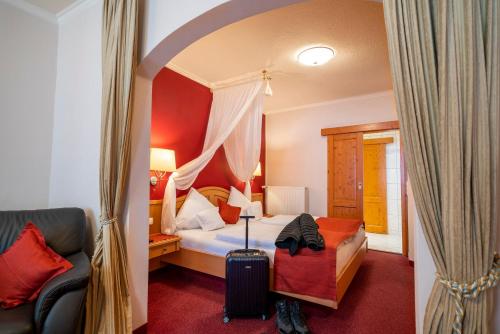 a bedroom with a bed and a chair and a suitcase at Altkölnischer Hof in Bacharach