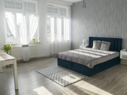 a bedroom with a blue bed in a room with windows at Apartamenty Pod Fortami in Przemyśl