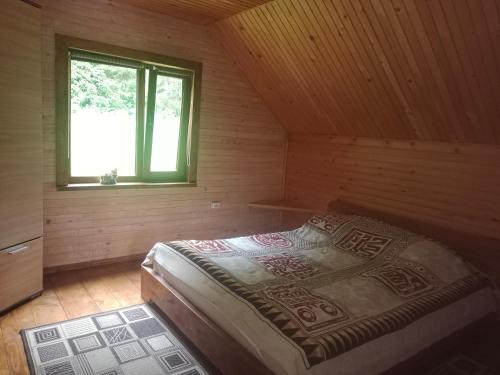 een slaapkamer met een bed in een houten hut bij Під горою in Sheshory