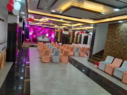 a banquet hall with orange and white chairs and a stage at Rich Grand Hotel in Agra