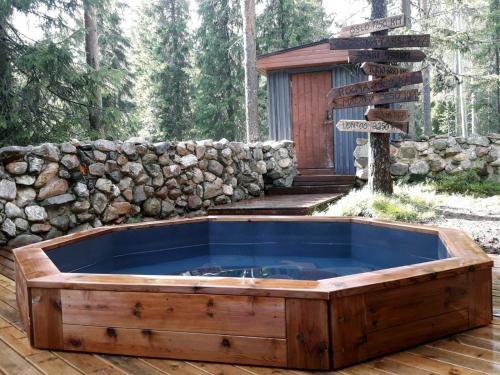 a hot tub on a deck next to a stone wall at Rovanperän kelomökit in Syöte