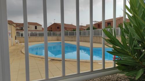 - une vue sur la piscine à travers une clôture dans l'établissement maison de vacances climatisée 5 pers avec piscine commune et vélos, à Gruissan