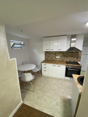 una cucina con mobili bianchi, tavolo e sedie di Baron Apartment a Belgrado