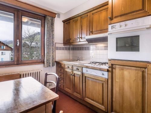 une cuisine avec des armoires en bois, une table et une fenêtre dans l'établissement Studio cosy 30m², proche pistes ski et centre, balcon, parking, wifi, animaux acceptés - FR-1-453-187, à Megève