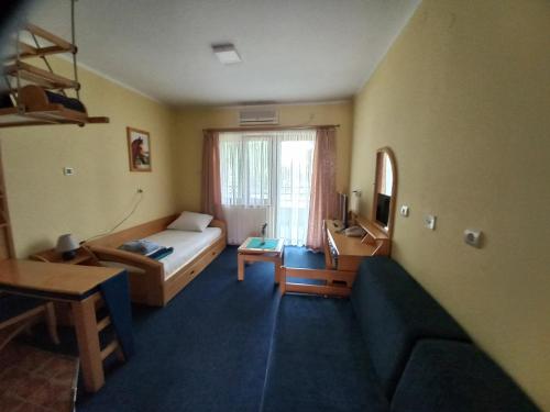 a room with a bed and a couch and a television at Garni Lupus prenoćište in Kanjiža