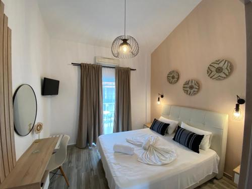 a bedroom with a white bed and a table and a mirror at Christina Apartments in Fourka
