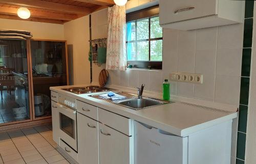 cocina blanca con fregadero y fogones en Blaues Haus by Rujana, en Zirkow