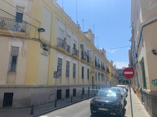 une voiture garée dans une rue à côté des bâtiments dans l'établissement LA CASITA DE LA PUERTA DE CARMONA, à Séville