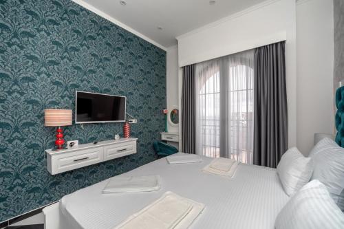a bedroom with a bed and a tv on a wall at Baba's Hotel & Spa in Dobra Voda