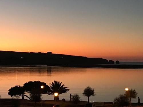 a sunset over a body of water with palm trees at Hotel Milagros Golf in Mogro