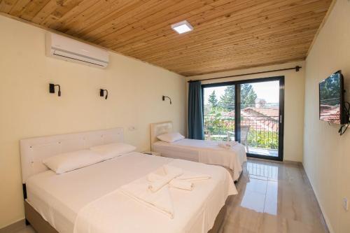two beds in a room with a large window at Beyoglu Pansiyon in Patara