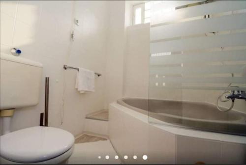a white bathroom with a toilet and a bath tub at Gallery flat in Party district in Budapest