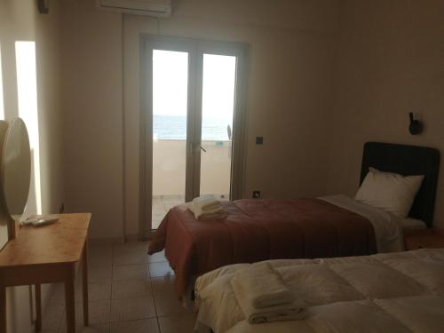 a bedroom with two beds and a view of the ocean at Filanthi CostaS in Stoupa