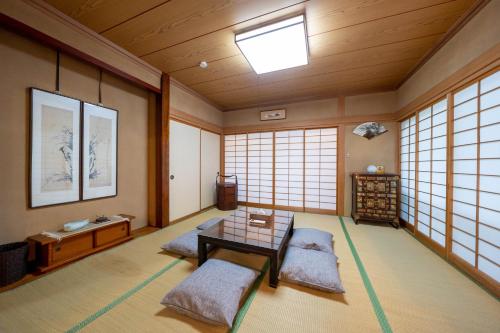 Zimmer mit einem Tisch und Stühlen in einem Zimmer mit Fenstern in der Unterkunft スイートヴィラ アンジュール 小淵沢高原 in Iwa-kubo