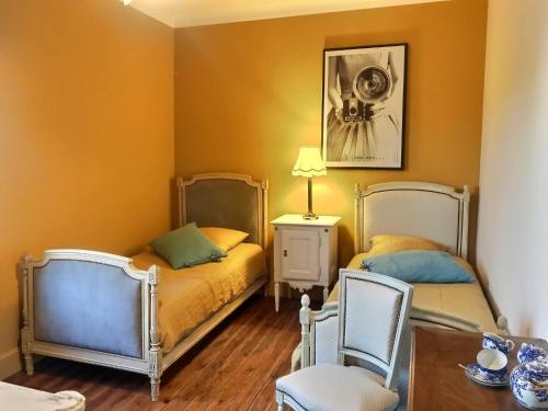 2 camas en una habitación con paredes de color naranja en chambres d'hôtes maison de charme, en La Boissière-de-Montaigu