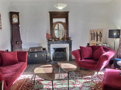 sala de estar con 2 sillas rojas y chimenea en chambres d'hôtes maison de charme, en La Boissière-de-Montaigu