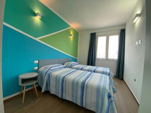 2 camas en una habitación con paredes azules y verdes en Casa Meli, en San Vero Milis