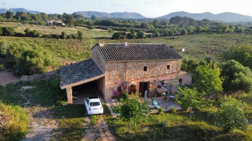 una furgoneta blanca estacionada frente a una casa de piedra en Sa Riba, Country house in Mallorca, en Son Carrió