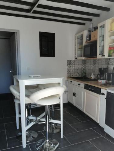 une cuisine avec une table blanche et un tabouret dans l'établissement Gîtes des marais du Lozon - Maison à la campagne, à Remilly-sur-Lozon