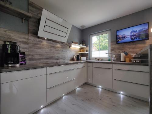 a kitchen with white cabinets and a tv on the wall at Ferienhaus Villa Adelsberg mit Dachterrasse in Zentraler Lage für bis zu 10 Personen in Chemnitz