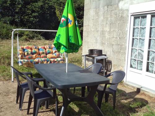 a picnic table with a green umbrella and chairs at Gîtes des marais du Lozon - Maison à la campagne in Remilly-sur-Lozon
