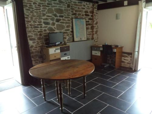 a wooden table in a room with a brick wall at Gîtes des marais du Lozon - Maison à la campagne in Remilly-sur-Lozon