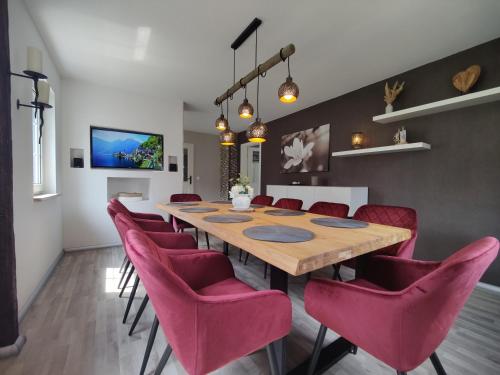 un comedor con una mesa larga y sillas rosas en Ferienhaus Villa Adelsberg mit Dachterrasse in Zentraler Lage für bis zu 10 Personen, en Chemnitz