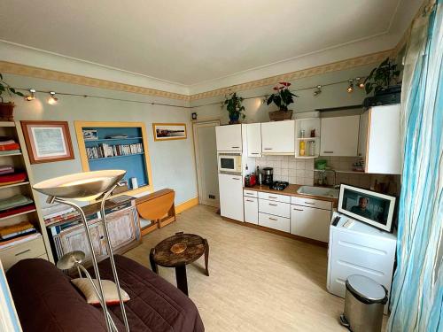 une cuisine avec des armoires blanches et un canapé dans une pièce dans l'établissement T2 à pied de plage sur ancien hôtel chic, samedi a samedi, à Saint-Jean-de-Luz