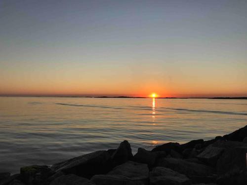 a sunset over a body of water with rocks at Kullavik, 2 mil från Göteborg Villa Gläntan in Kullavik