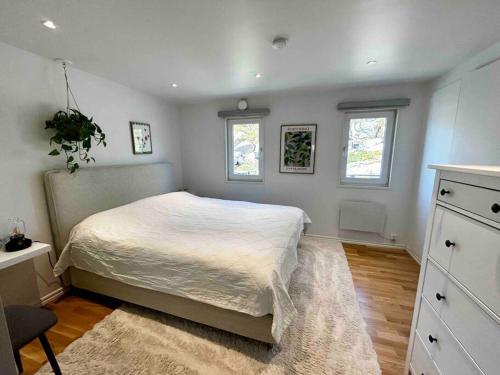 a bedroom with a large bed and two windows at Kullavik, 2 mil från Göteborg Villa Gläntan in Kullavik