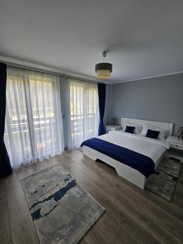 a bedroom with a large bed and large windows at Relax and Smile Rameț in Biceşti