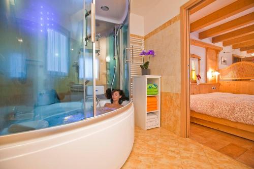 a woman in a bath tub in a bedroom at Albergo San Rocco in Peio