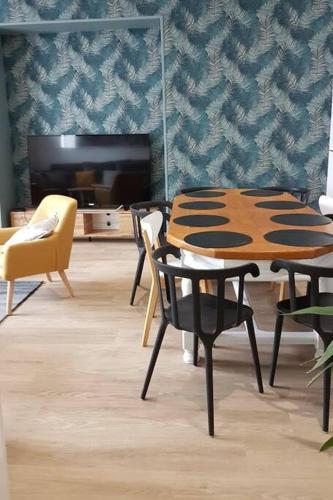 une pièce avec une table, des chaises et une télévision dans l'établissement Maison familiale en centre ville de Châteaulin, à Châteaulin