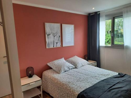 une chambre avec un lit et un mur rouge dans l'établissement Maison familiale en centre ville de Châteaulin, à Châteaulin