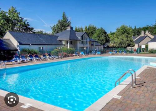 a large blue swimming pool with chairs in front of a house at Maison au calme à l'intérieur du golf de Ploëmel, entre terre et mer, 2 chambres, 10 min des plages in Ploemel