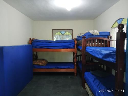 um quarto com 3 beliches com lençóis azuis em SÍTIO CONQUISTA FELIZ em Nova Iguaçu