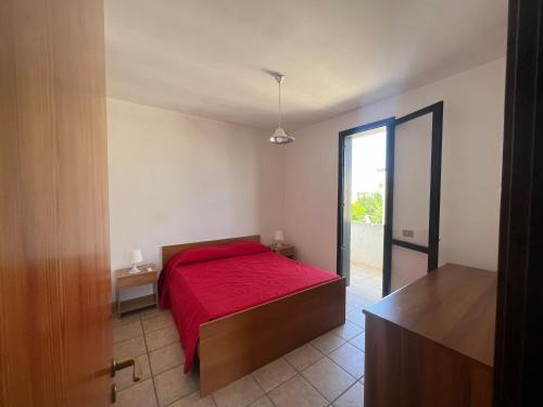 um quarto com uma cama com um cobertor vermelho em Mya Vacanze em Torre dell'Orso