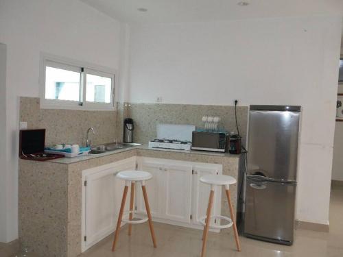 een keuken met een roestvrijstalen koelkast en 2 krukken bij Bel appartement à Liberté 6 extension in Dakar