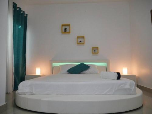 ein weißes Bett in einem Schlafzimmer mit zwei Lichtern in der Unterkunft Bel appartement à Liberté 6 extension in Dakar