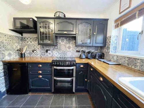 a kitchen with dark blue cabinets and a sink at 2 bed Victorian Cottage, log burner & garden room. in Dorney