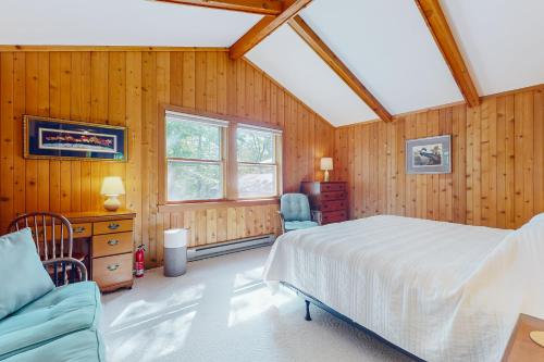ein Schlafzimmer mit Holzwänden, einem Bett und einem Sofa in der Unterkunft Snowflake Cabin in Barnumville