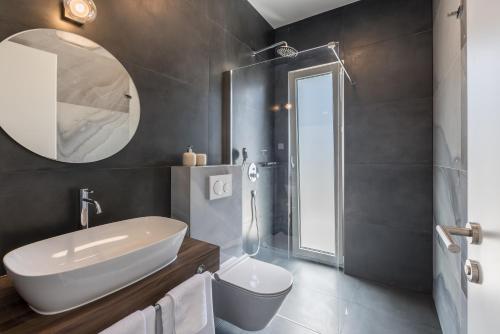 een badkamer met een wastafel, een toilet en een spiegel bij Villa Callista in Žrnovnica