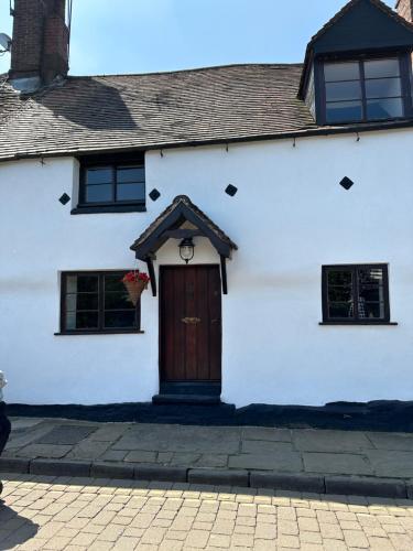 a white house with a brown door and windows at Bewdley River Cottage - Free private gated parking for 2 cars - River front location in Bewdley