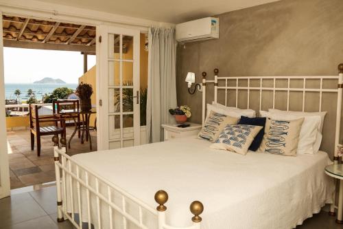 1 dormitorio con cama blanca y vistas al océano en Pousada Baía Bonita, en Búzios