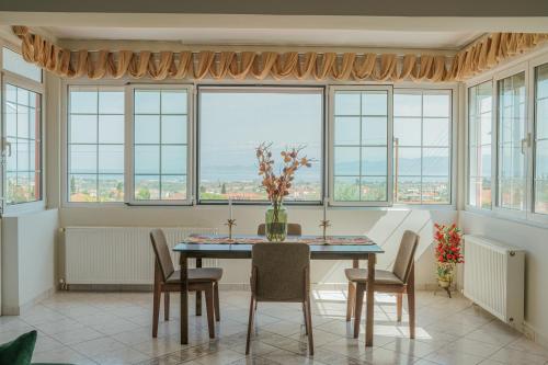 ein Esszimmer mit einem Tisch, Stühlen und Fenstern in der Unterkunft AKANTHOS Rental House in Kórinthos