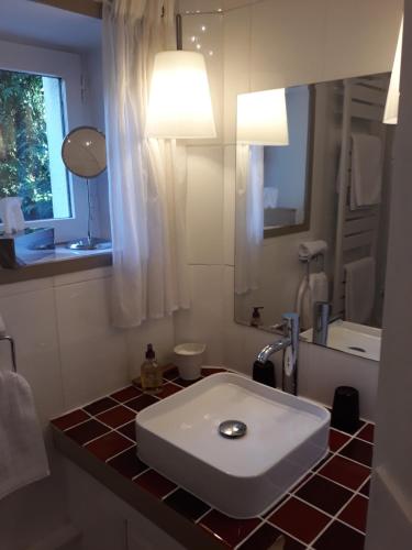 W łazience znajduje się biała umywalka i lustro. w obiekcie Maison Epellius w mieście Collonges-au-Mont-dʼOr