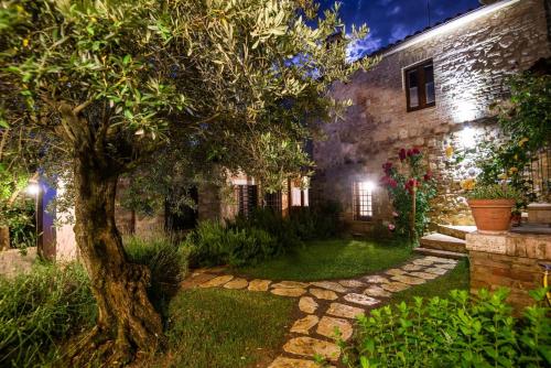 a stone house with a tree in the yard at BorgoCuore in Todi