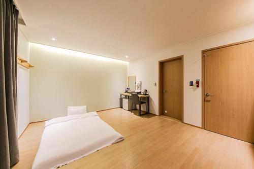 a bedroom with a white bed and a wooden door at 어라연 관광호텔 영월 in Yeongwol