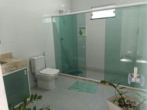 a bathroom with a toilet and a glass shower at Casa de praia em Barra do Gil in Vera Cruz de Itaparica