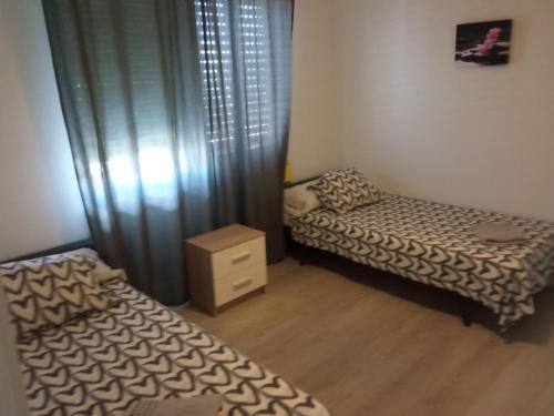 1 Schlafzimmer mit 2 Betten, einer Kommode und Vorhängen in der Unterkunft PISO PLAZA CABECEO in Jerez de la Frontera